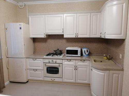 kuchnia z białymi szafkami i białą lodówką w obiekcie Апартаменты, Московская 97 w mieście Piatigorsk