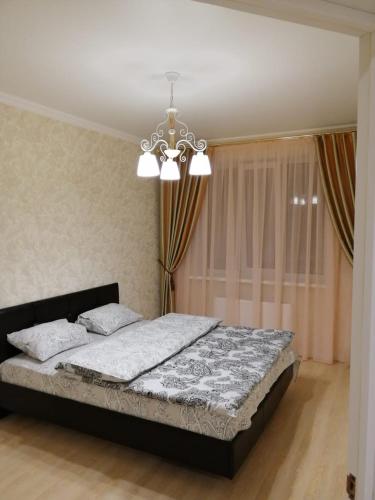 um quarto com uma cama e um lustre em Апартаменты, Московская 97 em Pyatigorsk