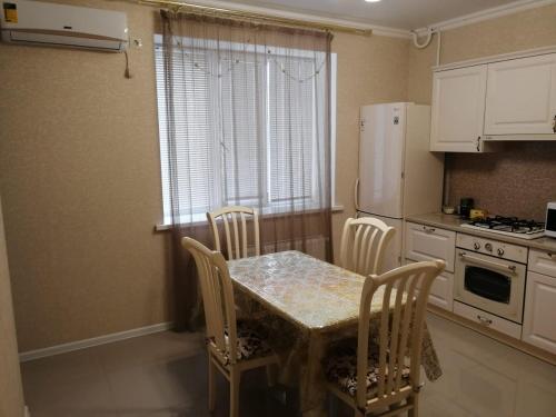 uma cozinha com uma mesa e cadeiras e um frigorífico em Апартаменты, Московская 97 em Pyatigorsk