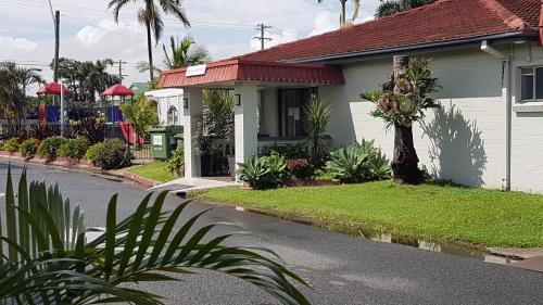 una casa blanca con techo rojo en una calle en Tropic Coast Motel en Mackay