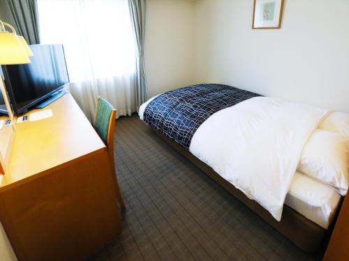 a bedroom with a bed and a desk and a television at APA Hotel Obihiro Ekimae in Obihiro
