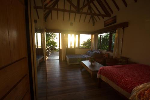 a living room with a bed and a couch and windows at Boa Hill Surf House in Nembrala