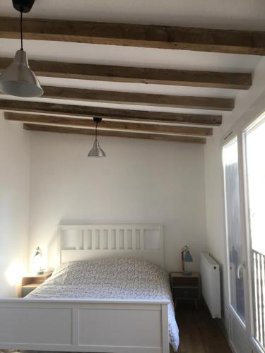 Schlafzimmer mit einem weißen Bett und Holzdecken in der Unterkunft Maison de bourg avec cour privée in Tallende