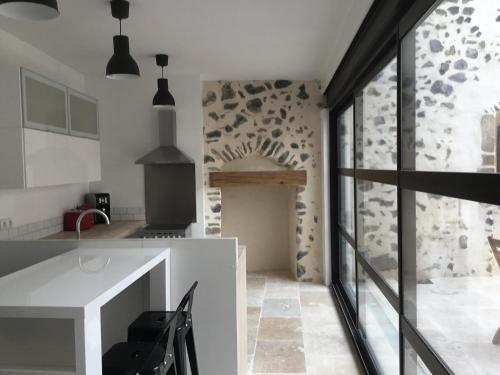 eine Küche mit einer weißen Theke und einer Steinmauer in der Unterkunft Maison de bourg avec cour privée in Tallende