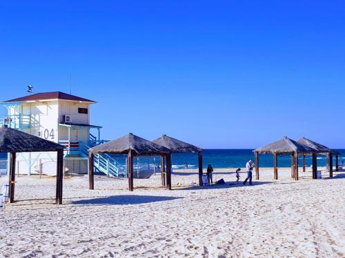 a group of umbrellas on a beach with the ocean at Spat Hotel Ashdod in Ashdod