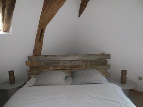 a bedroom with a wooden headboard and a white bed at Les jardins de Peychenval in Lamonzie-Montastruc