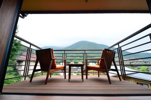 2 Stühle und ein Tisch auf einem Balkon mit Aussicht in der Unterkunft Hakone Onsen Ryokan Yaeikan in Hakone