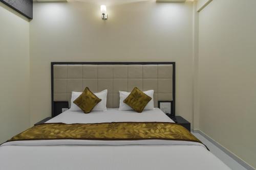 a bedroom with a large white bed with gold pillows at Hotel Aroma- Dadar in Mumbai