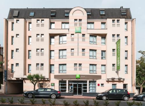 a large pink building with cars parked in front of it at Hôtel ibis Styles Vichy Centre in Vichy