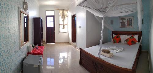 a bedroom with a bed with a canopy at Mocco Beach Villa in Kendwa