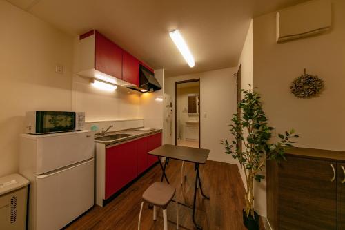 a small kitchen with red cabinets and a stool in it at Apartment Heights HANA in Sakai