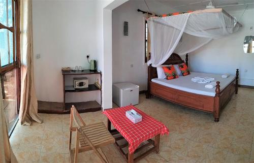1 dormitorio con 1 cama, mesa y sillas en Mocco Beach Villa, en Kendwa