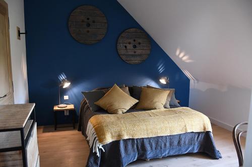 a bedroom with a blue wall and a bed with pillows at Domaine de La Lochetière Chambres d'hôtes in Normandel