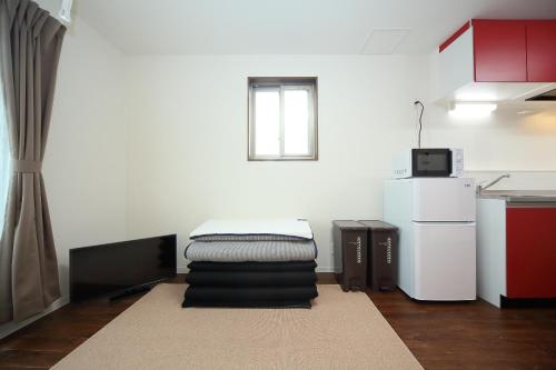 a small room with a bed and a refrigerator at Apartment Heights HANA in Sakai