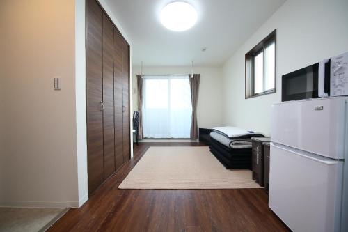 a room with a kitchen with a refrigerator and a couch at Apartment Heights HANA in Sakai