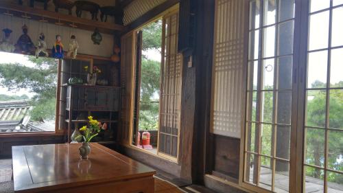 a room with windows and a table with flowers on it at Ahndong Kimjongtaek Yangsodang in Andong