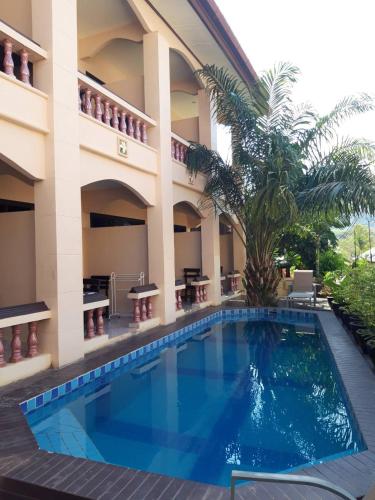 a swimming pool in front of a building with a palm tree at Thalassa in Nai Harn Beach