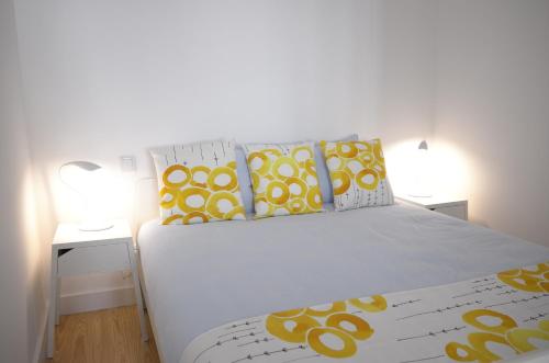 a bedroom with a white bed with yellow and white pillows at Double Suite by the Ocean in Paço de Arcos
