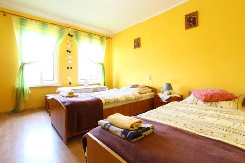 a yellow room with three beds and a window at Pokoje Stefania in Międzyzdroje