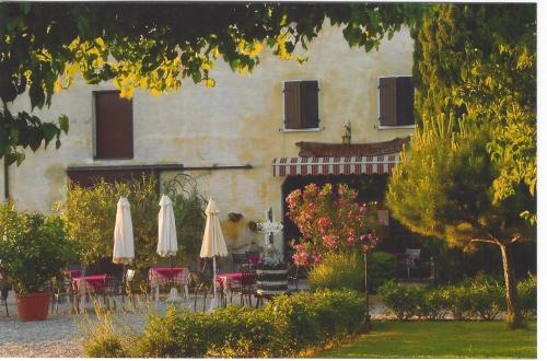 a building with umbrellas and tables and chairs at Agriturismo Le Caldane in Colà di Lazise