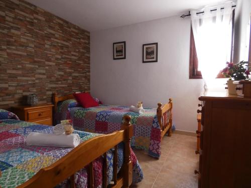 1 dormitorio con 2 camas individuales y pared de ladrillo en La Ruella, en Cerviá
