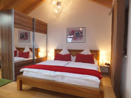 1 dormitorio con 1 cama grande con almohadas rojas en Ferienwohnung Alpenstern, en Rieden