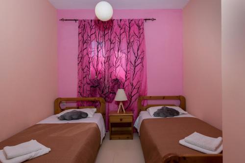 two beds in a room with pink and purple walls at Eleni's cozy apartment in Tsilivi in Gaïtánion