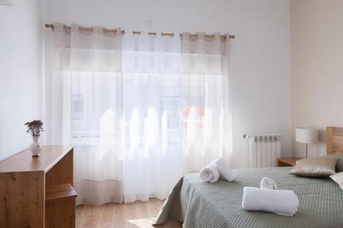 a white bedroom with a bed and a window at Quinta de Trancoso in Carnicãis