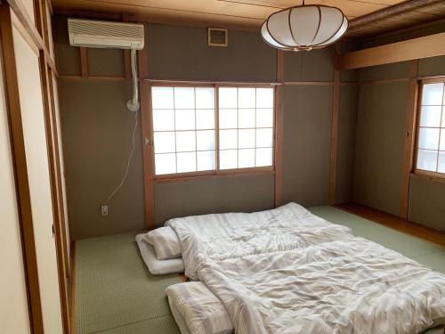 a bedroom with a large bed and two windows at Hostel Jumpu Manpan in Otaru