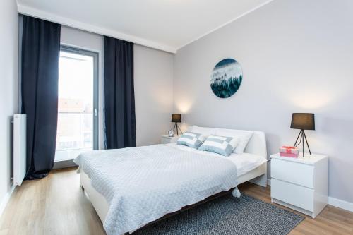 a white bedroom with a bed and a window at Seaside Beach 150m do Plaży - Praia Apartments - Polsat Plus Arena in Gdańsk