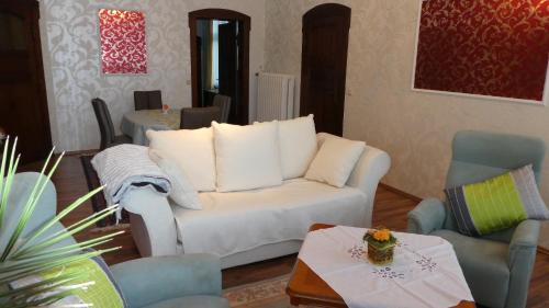 a living room with a white couch and two chairs at Villa Charlotte in Bad Liebenstein