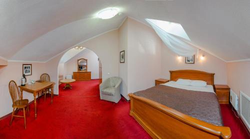 1 dormitorio con cama, escritorio y mesa en Voskresenskaya Hotel, en Cherepovets