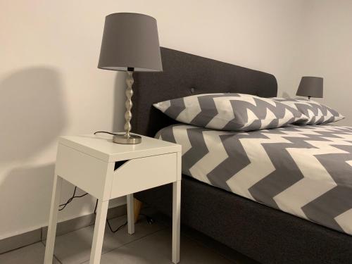 a bed with a white nightstand and a lamp on a side table at Aurora Zagreb in Zagreb