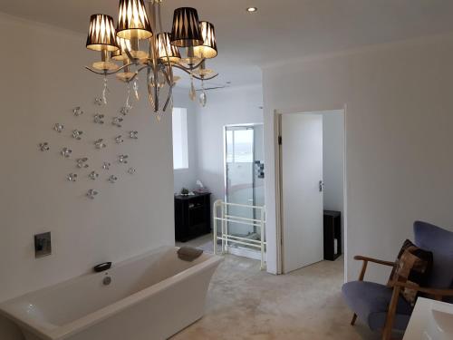 a white bathroom with a tub and a chandelier at Atlantic Loft - Open plan apartment with Sea Views in Melkbosstrand