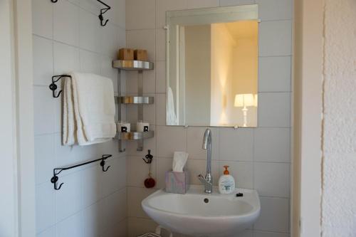 Baño blanco con lavabo y espejo en Beej Potters, en Weert