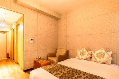 a hotel room with two beds and a chair at Condominium Hotel Likka in Nago in Nago