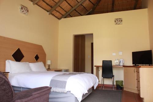 a bedroom with a bed and a desk and a television at Black Swan Guesthouse in Maseru