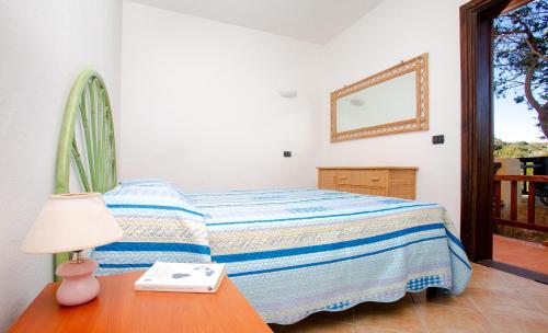 a bedroom with a bed and a table with a lamp at Residence La Marmorata in Santa Teresa Gallura