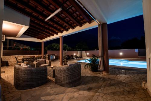 an outdoor patio with couches and a pool at night at Villa Komel with Pool in Fažana