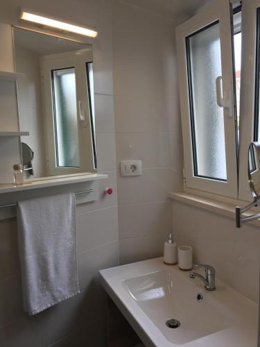 a white bathroom with a sink and a mirror at House Olivia in Pučišća