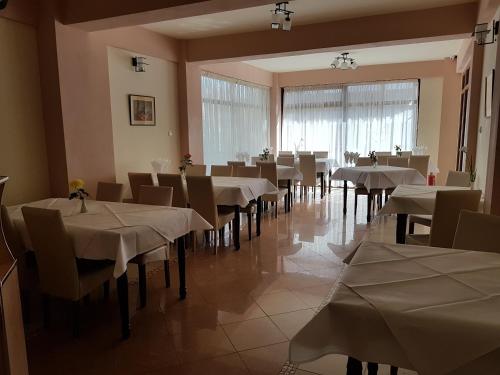 a restaurant with white tables and chairs and a large window at Vila Orhidee in Eforie Nord