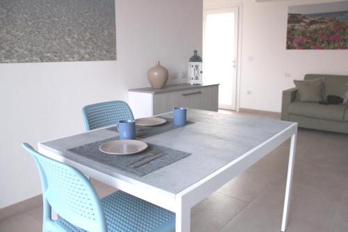a white dining room table with blue cups and plates on it at 197 Pozzo San Nicola in Stintino