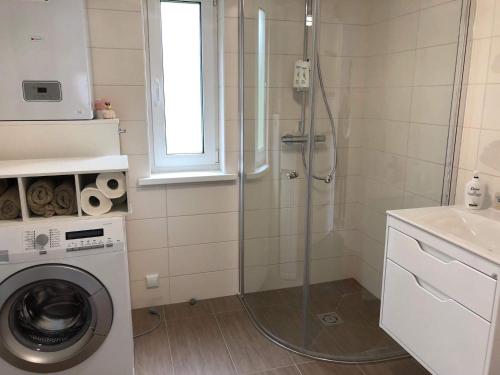 een badkamer met een douche en een wasmachine bij FREGO house in Anykščiai