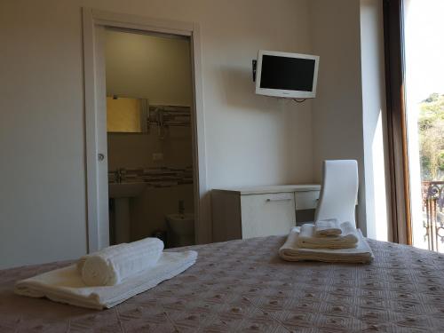 1 dormitorio con 1 cama con toallas y TV en la pared en Giò Rooms, en Scalea