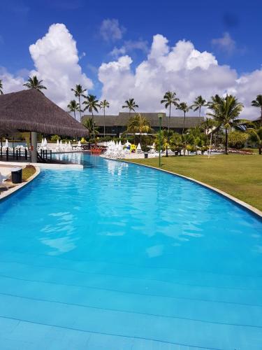 a large blue swimming pool with palm trees at Flat Beach Class Resort Muro Alto in Porto De Galinhas