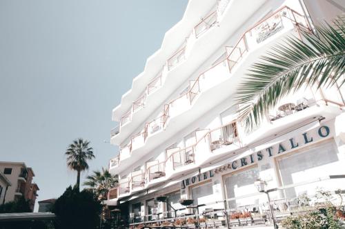 ヴァラッツェにあるHotel Cristalloのテーブルと椅子が備わる白い大きな建物
