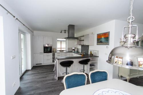 uma cozinha com armários brancos e uma mesa e cadeiras em Ferienhaus Harmonia em Neuendorf Heide