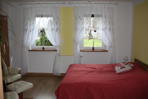 a bedroom with a red bed and two windows at Ferienwohnung Scharnhorst in Dresden