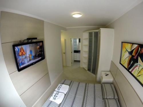 Habitación pequeña con TV en la pared en Apartamento Canasvieiras en Florianópolis