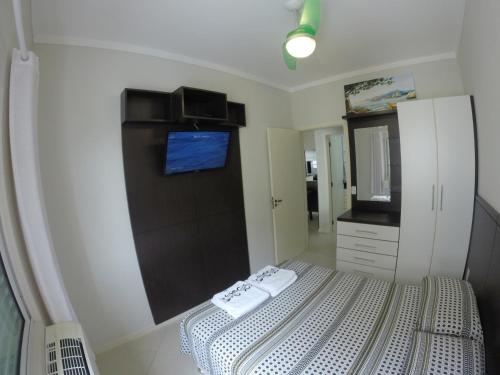 Dormitorio pequeño con cama y espejo en Apartamento Canasvieiras en Florianópolis